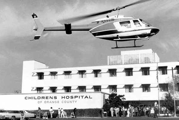 People on the ground with helicopter flying over hospital
