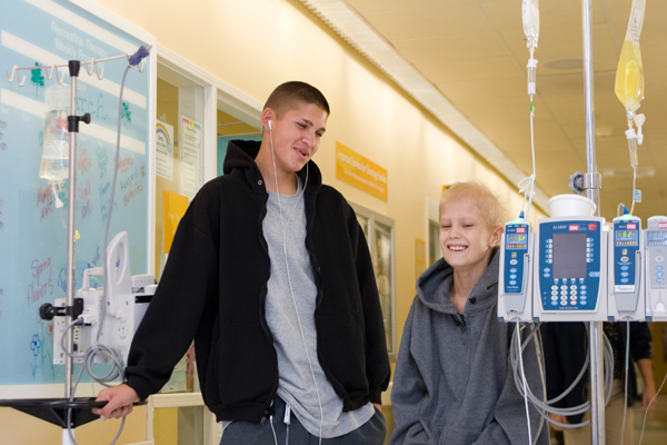 Two cancer teen patients walking in the hospital hallway