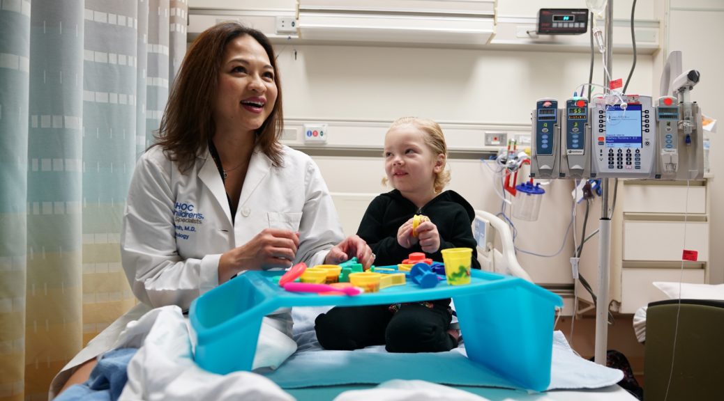 CHOC oncologist playing with blocks with young patient on hospital bed