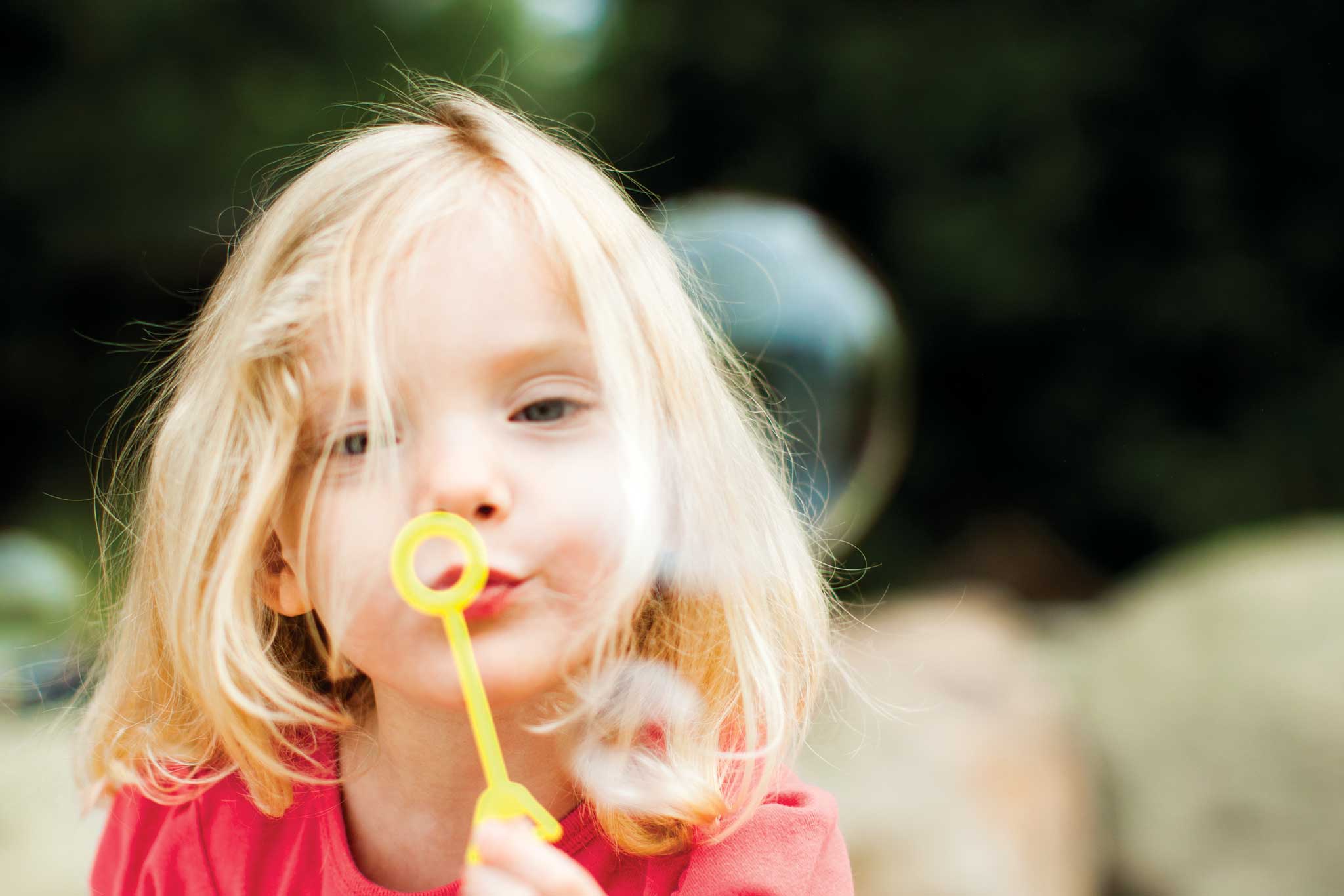 Young blond girl blowing bubbles