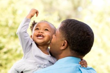 father carries young daughter on shoulders