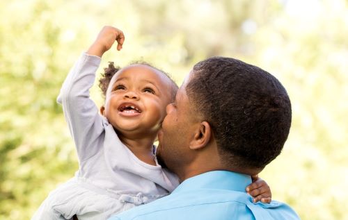 father carries young daughter on shoulders