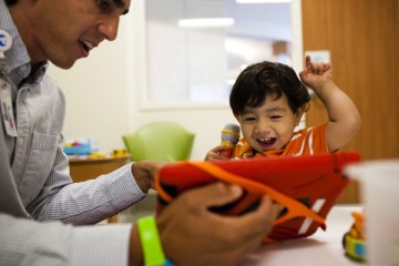 Child life specialist plaing with smiling young boy in the playroom