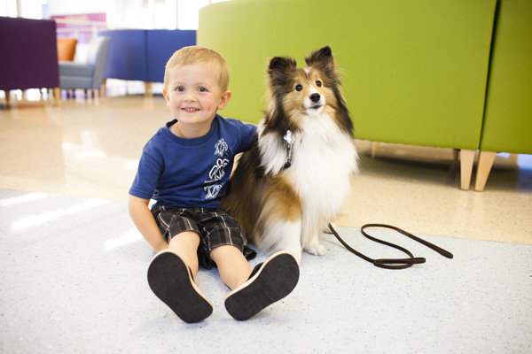 Young boy sitting on floor with pet therapy dog