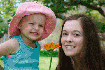 Mom and child smiling by a garden