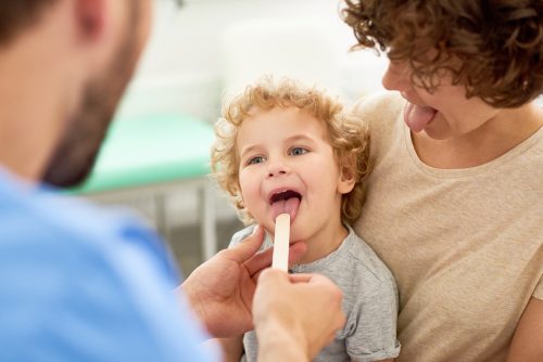 young boy getting tonsils checked at doctor's