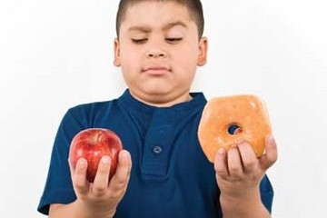 Boy deciding between an apple and a donut