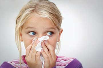 Young girl blowing her nose using a tissue