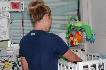 Nurse by a crib in the NICU