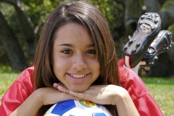 Girl soccer player with her chin on the ball