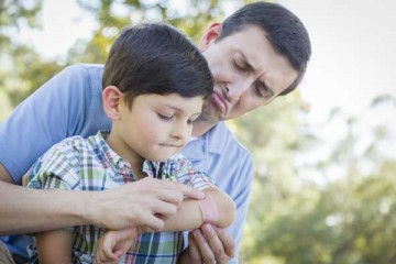 Dad helping son with band-aid