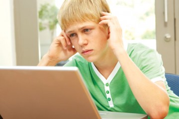Boy looking at computer screen with worried look on his face