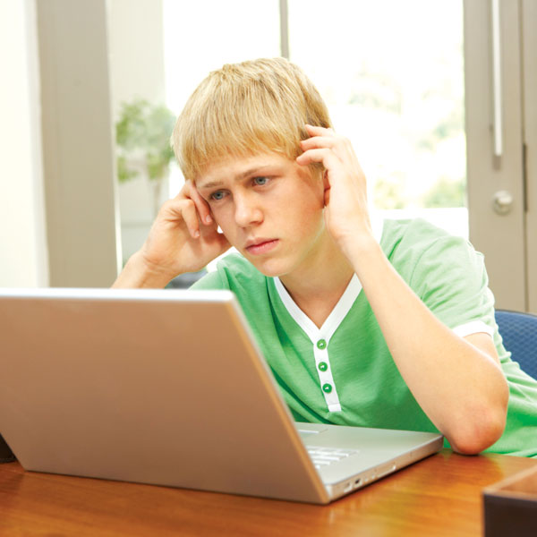 Boy looking at computer screen with worried look on his face