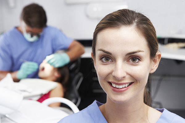 Dental assistant with dentist and patient in the background