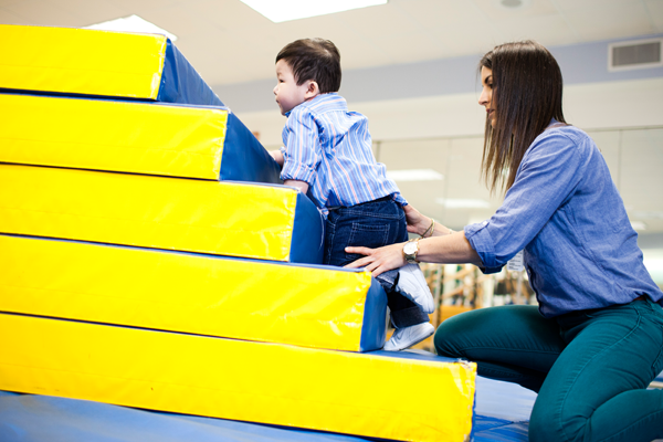 toddler boy climbing steps in physical therapy