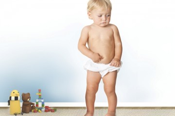 Toddler in diapers with his finger on his belly button