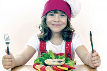 Kid holding fork and knife with a healthy plate of food