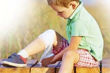 Small child wrapping bandage around his knee