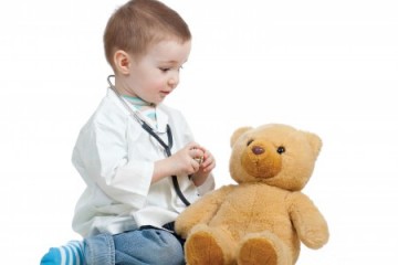 Little boy playing doctor with his bear