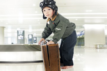 Young boy dressed like a pilot with suitcase at the airport