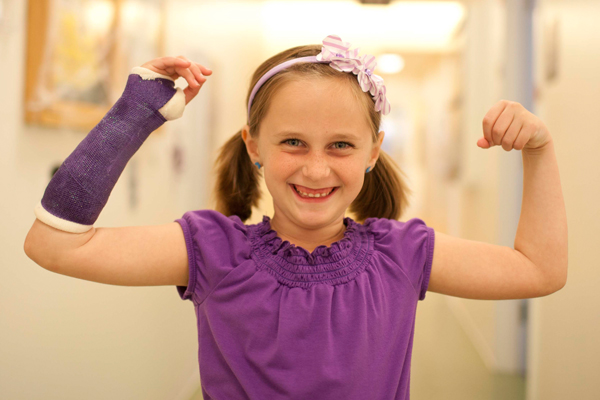 Proud smiling young girl with cast on her arm