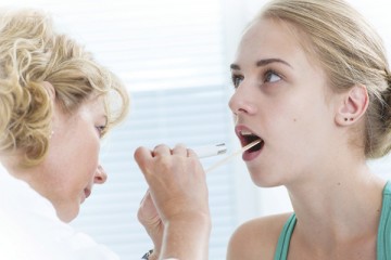 Physician looking at the throat of teenage girl