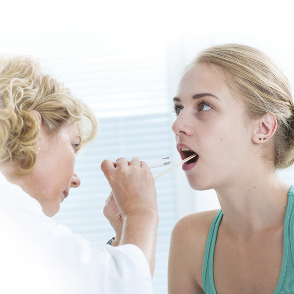 Physician looking at the throat of teenage girl