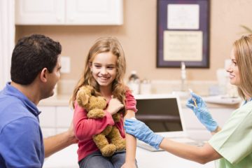 Kind female nurse gives a little girl patient a vaccine