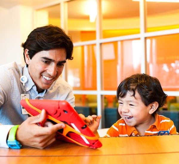 Boy laughing as volunteer shows games on an ipad