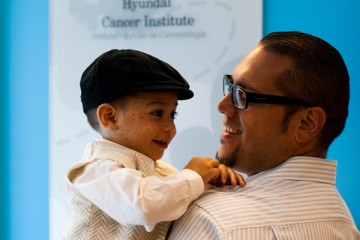 Father holding son in front of the Hyundai Cancer Institute