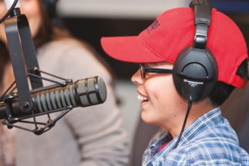 Smiling young boy speaking into the microphone in the Seacrest Studio