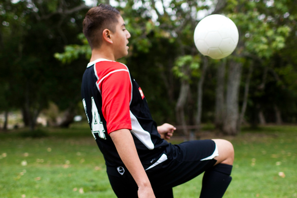 Boy soccer player bouncing ball on his knee