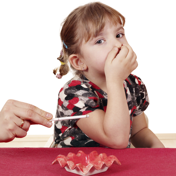 Little girl holding her nose with lighted cigarette near