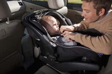Father securing infant in car seat