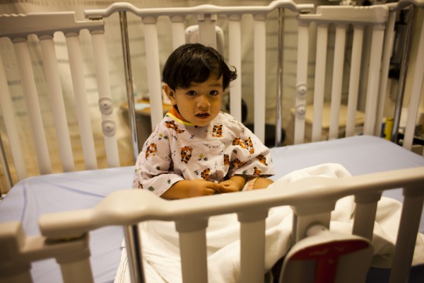 Little boy sitting in a presurgery crib