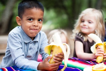 Girl and boy eating bananas