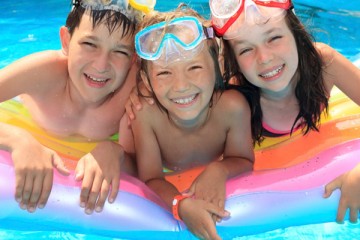 Three kids with goggles in the pool