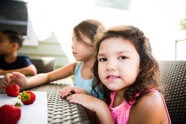 Kids at a patio table with strawberries