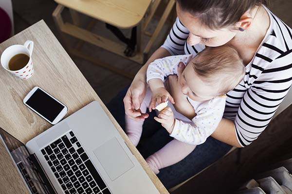 Mom holding baby while looking at computer