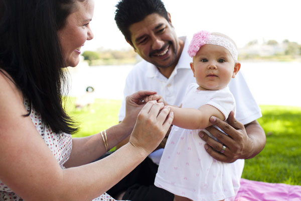 Baby girl standing with parents