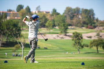 Man swinging club on golf course