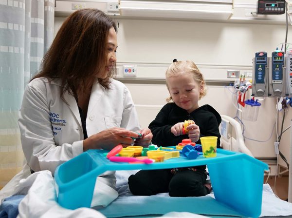 Child playing with Playdoh while physician visits
