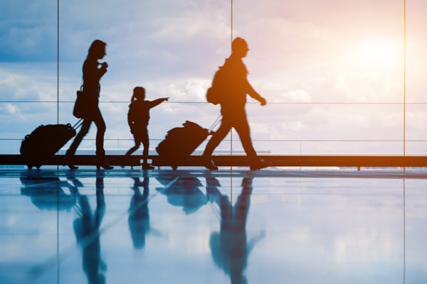 Family waking through airport terminal pulling their suitcases