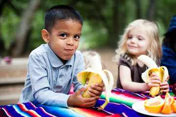 two kids eating bananas
