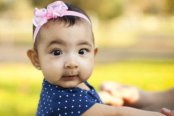 baby infant girl with pink bow and blue polka dots, mom holding arms