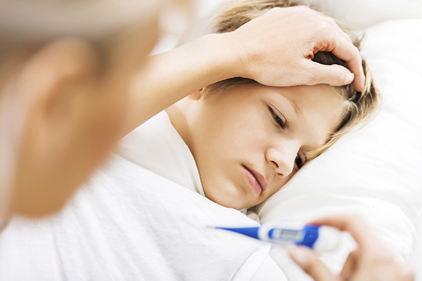 Young boy sick in bed and gets temperature checked