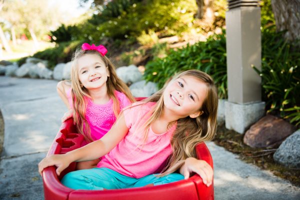 Two smiling girls sitting in a red wagon