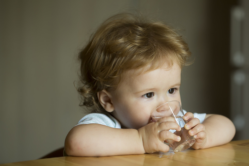 Young child drinking water at table