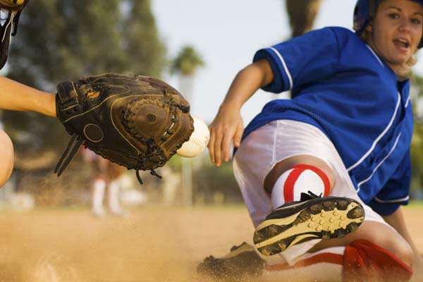 Softball player sliding into home plate