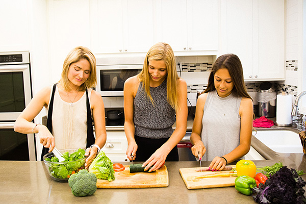 Teens and mom making salad in the kitchen
